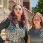 Two teenage girls pose in front of a courthouse.