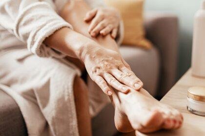 woman putting lotion on feet