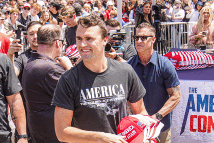 Charlie Kirk smiling while throwing MAGA hats