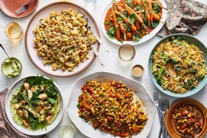 An overhead image of table set with various salad platters, piled high with vegetables.