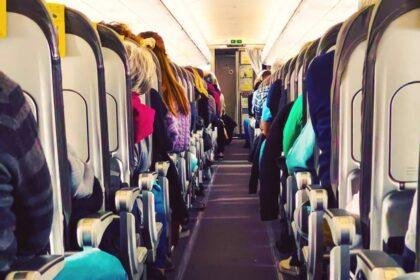 Picture during flight in a commercial airplane full with people sitting in seats taken picture from the end of the aisle with nice vanishing point.