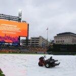 A tarp covers the field as rain falls while a message is seen on a video board alerting fans the start of Game 3 of baseball's American League Division Series between the Detroit Tigers and the Seattle Mariners will be delayed Tuesday, Oct. 7, 2025, in Detroit.(AP Photo/Ryan Sun)