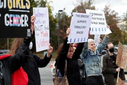 Photo shows people protesting in Loudoun County Virginia against school policies and holding signs in 2021