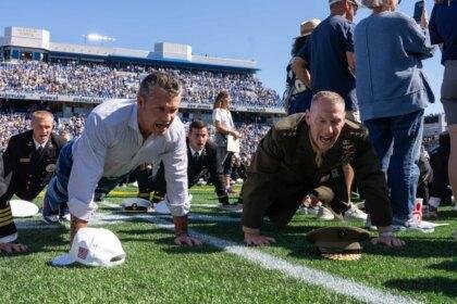 Secretary of War Pete Hegseth and Marine Corps Lieutenant General Michael J. Borgschulte participating in a push-up world record attempt at the Navy vs. Air Force football game.
